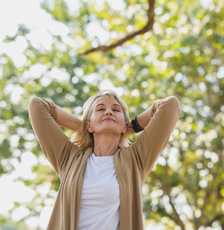 BODYMIND CAMPUS glückliche Frau durch Seminar zum Thema Stressmanagement Glückliche ältere Dame, die mit hinter dem Kopf verschränkten Armen entspannt in den Himmel lächelt